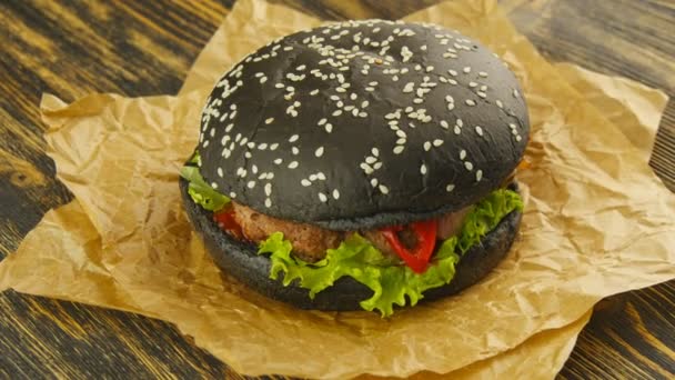 Černá burger na dřevěný stůl - Záběry, video
