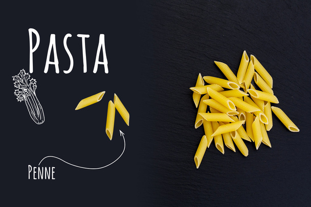 Uncooked Italian pasta Penne on black slate stone background - 写真・画像