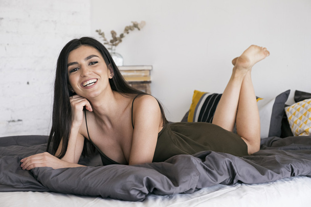 Laughing girl on bed in morning - Foto, afbeelding