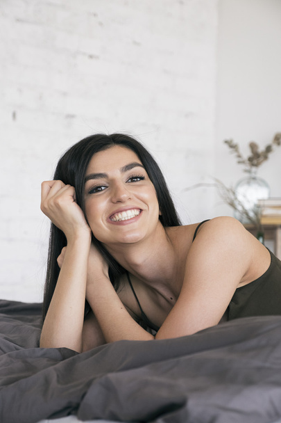 Cheerful black-haired girl on bed - 写真・画像