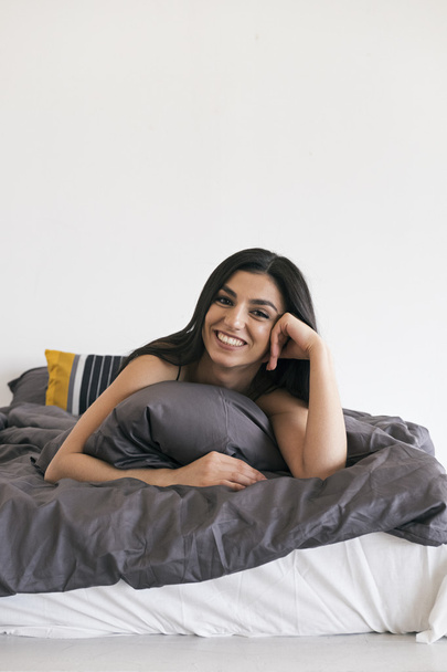 Cheerful girl on bed smiling at camera - Фото, изображение