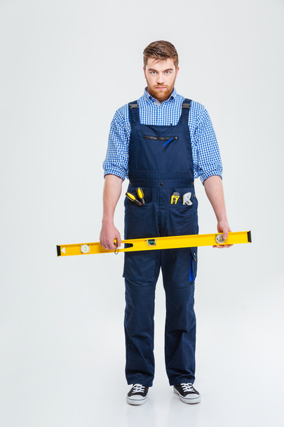 Serious male builder holding waterpas - Photo, image