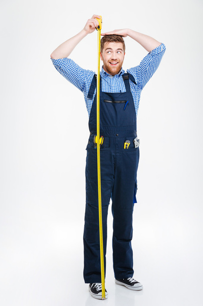 Happy funny young man measuring his body height using tape - Φωτογραφία, εικόνα