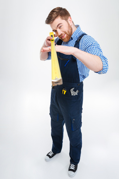 Handsome focused young man worker standing and using measuring tape - Фото, зображення