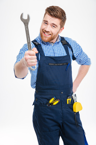 Smiling bearded young man standing and showing wrench - Zdjęcie, obraz