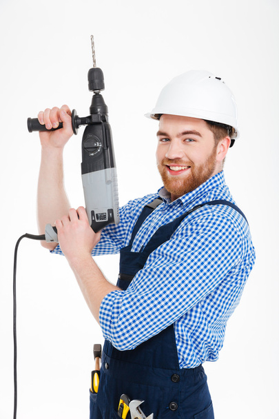 Happy attractive young worker standing and smiling using drill - Fotoğraf, Görsel
