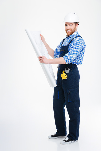 Smiling handsome young man builder standing and working with blueprint - Fotoğraf, Görsel