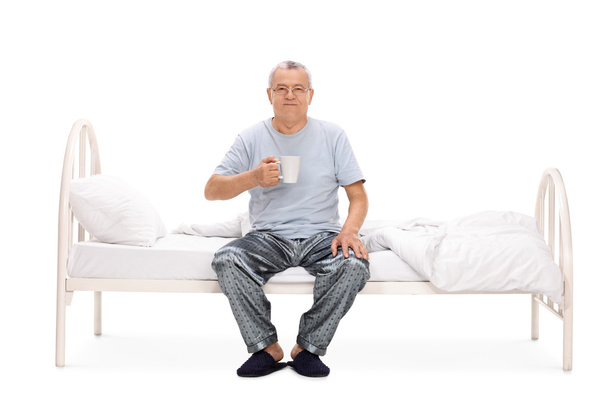 Hombre mayor sentado en la cama y tomando café
  - Foto, imagen