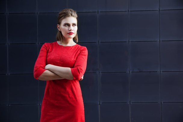 mooi meisje met make-up in een rode jurk in een moderne stad - Foto, afbeelding