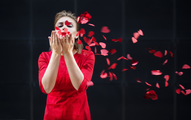 Ημέρα του Αγίου Βαλεντίνου έννοια, γυναίκας με κόκκινο φόρεμα που φυσά σε ένα χαρτί καρδιά. - Φωτογραφία, εικόνα