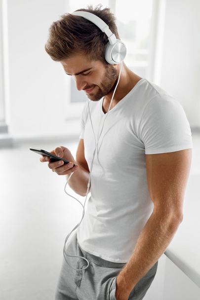Man Listening To Music In Headphones Using Mobile Phone Indoors - Fotoğraf, Görsel