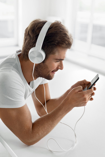 Music Listening. Man In Headphones Using Mobile Phone Indoors - Foto, afbeelding