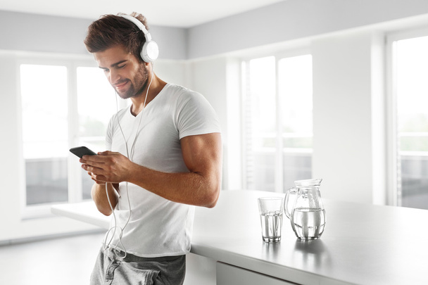 Man Listening To Music In Headphones Using Mobile Phone Indoors - Valokuva, kuva