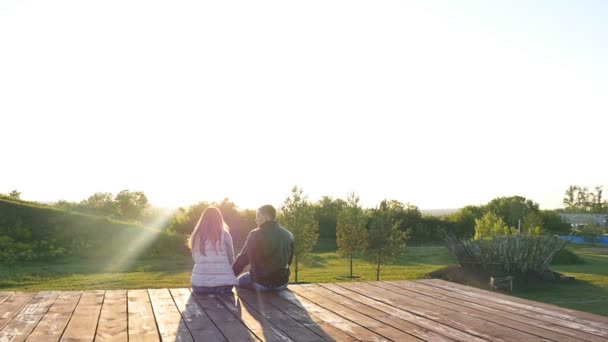 вид ззаду молода щаслива пара сидить на заході сонця
 - Кадри, відео