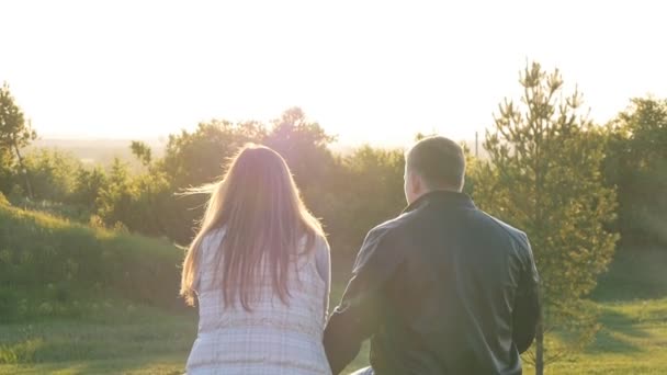 Powrót widzenia młoda szczęśliwa para siedzi o zachodzie słońca - Materiał filmowy, wideo