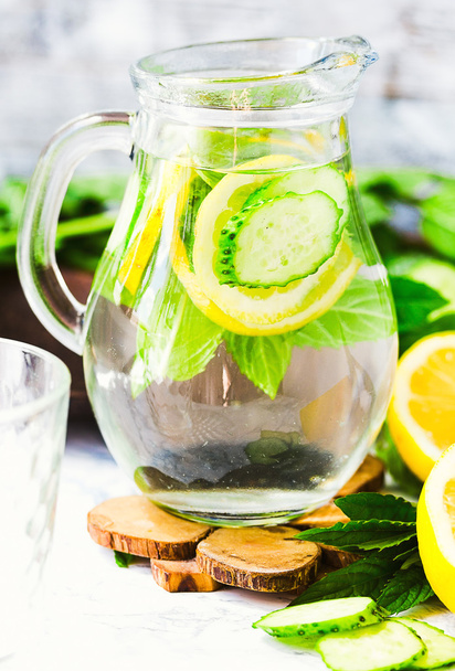 Water with lemon, mint and cucumber in glass,light background  - Фото, зображення