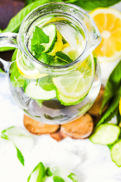 Water with lemon, mint and cucumber in glass,light background  - Фото, изображение