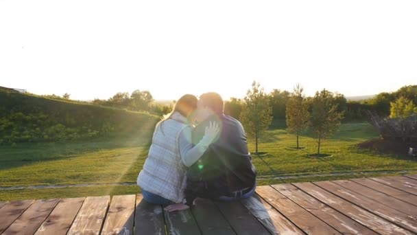 arkadan görünüşü günbatımında oturan genç mutlu çift - Video, Çekim