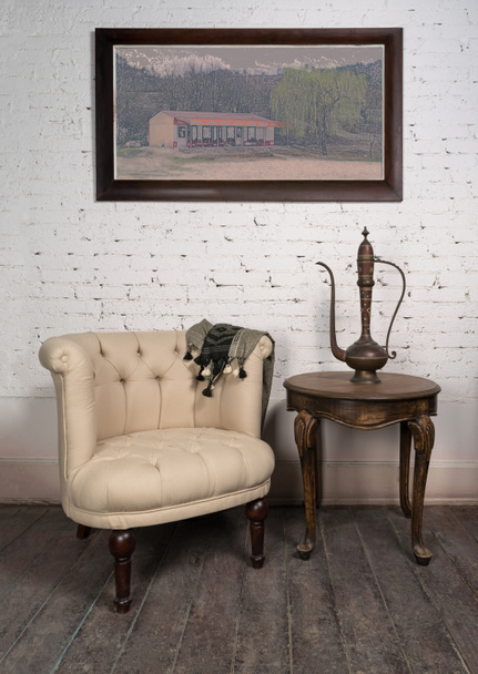 Oude beige fauteuil, messing theepot, ingelijste schilderijen en antieke tafel - Foto, afbeelding