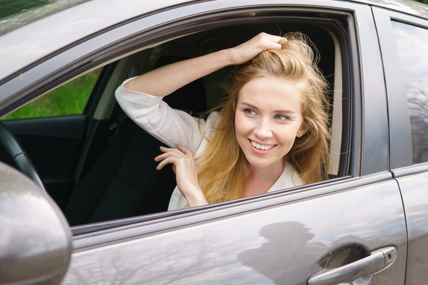 Χαμογελαστή γυναίκα που κάθεται στο αυτοκίνητο - Φωτογραφία, εικόνα