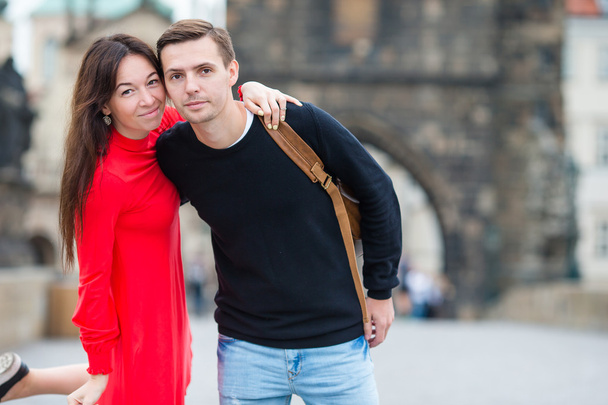 Coppia felice che cammina sul Ponte Carlo a Praga. Gli amanti sorridenti godendo paesaggio urbano con famosi punti di riferimento
. - Foto, immagini