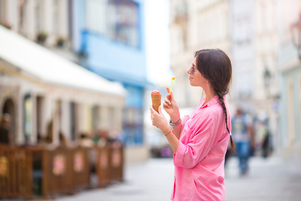Young female model eating ice cream cone outdoors. Summer concept - woamn with sweet ice-cream at hot day - Photo, Image