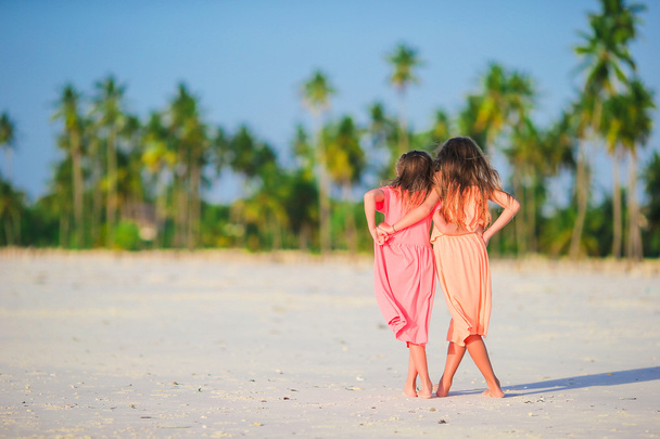 Adorable little kaukaski dziewczyny na plaży podczas letnich wakacji. Szczęśliwy kids wspólna zabawa na ich rodzinne wakacje. - Zdjęcie, obraz