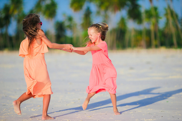 Чарівні маленькі кавказькі дівчата на пляжі під час літніх канікул. Щасливі діти розважаються разом у своїх сімейних літніх канікулах
. - Фото, зображення