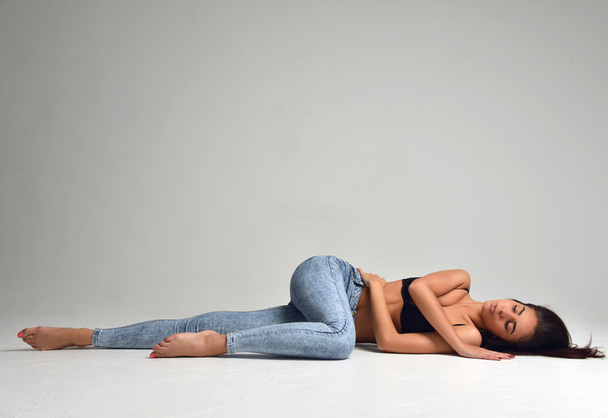 Slim beautiful brunette woman lying on a floor in sexy underwear - Fotoğraf, Görsel