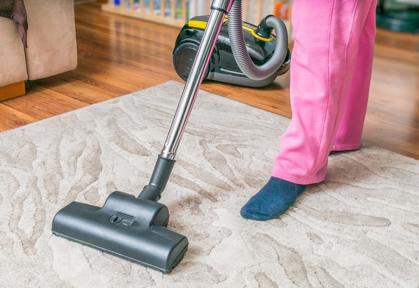 Woman is cleaning carpet with vacuum cleaner. - Fotoğraf, Görsel