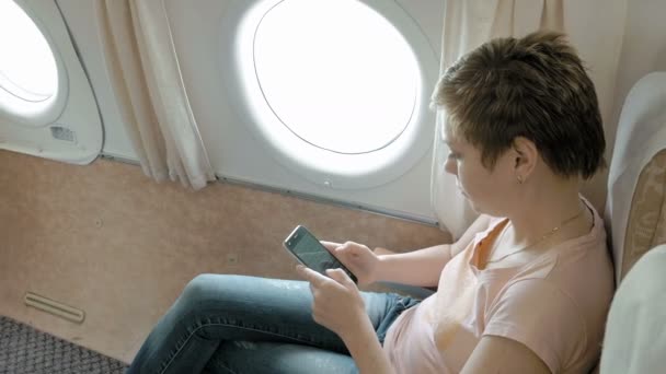 Pasajero del avión desplazándose a través del teléfono inteligente
 - Metraje, vídeo