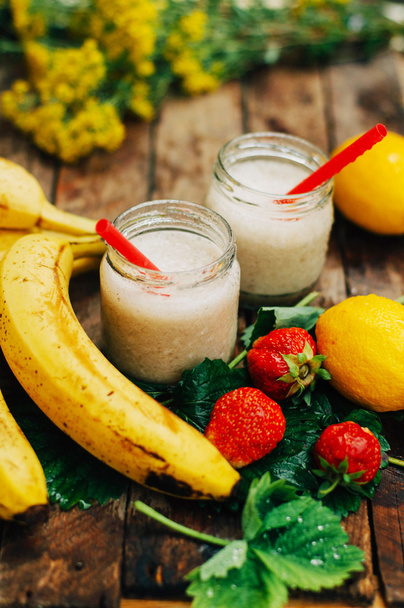 Fruit Smoothies. banana smoothies with milk. Banana Smoothie on a wooden table. Healthy breakfast: banana smoothie with oatmeal. Banana smoothie in glass with fresh fruits on wooden background - Photo, Image