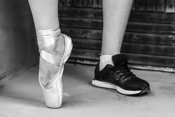 Pés vestidos com sapatos de pontas de dança e sapatos esportivos. Foto em preto e branco
 - Foto, Imagem