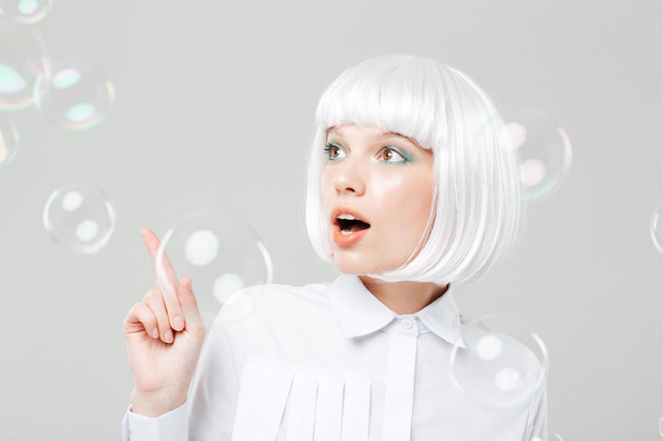 Lovely amazed woman looking at soap bubbles and pointing away - 写真・画像