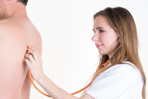 Вид збоку жінки-лікар оглядає спину пацієнта стетоскопом
 - Фото, зображення