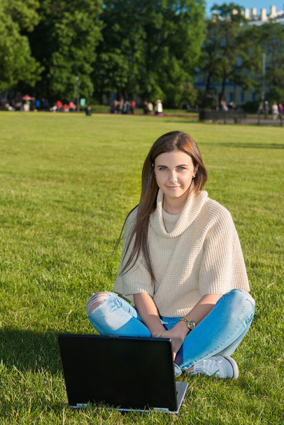 Молодая женщина на траве в парке или саду с помощью ноутбука
 - Фото, изображение