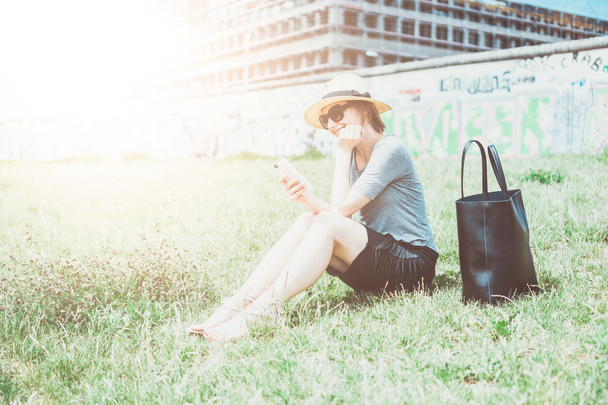 Одинокая молодая женщина в шляпе сидит на улице
 - Фото, изображение