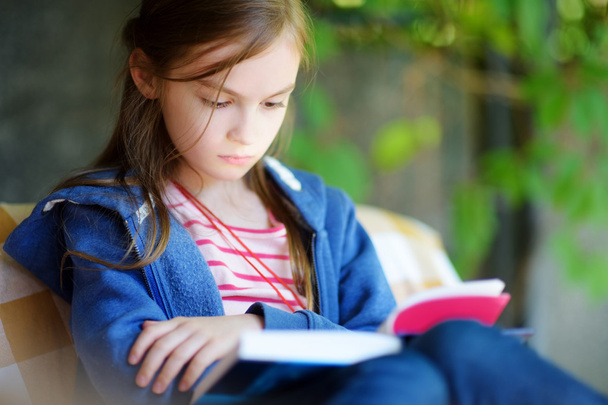 Cute little girl reading a book outdoors - Foto, Imagen