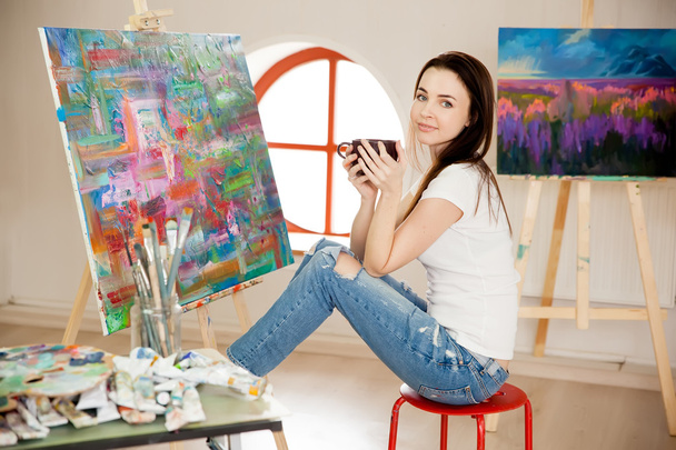 Female Artist Working On Painting In Studio - 写真・画像