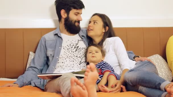 Famiglia felice, madre, padre e il loro bambino leggono un libro a casa
 - Filmati, video