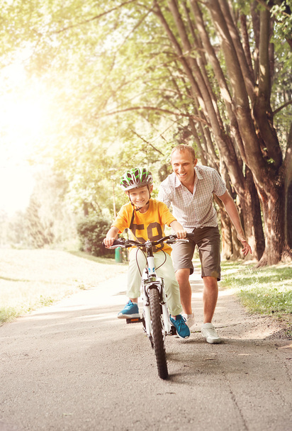 Vater zu seinem kleinen Sohn Fahrt Fahrrad helfen - Foto, Bild