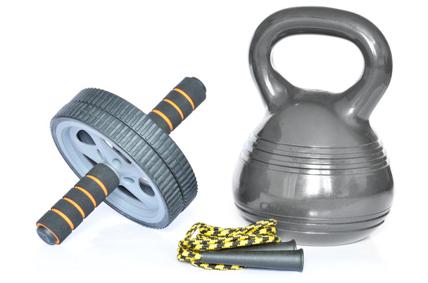Geïsoleerde kettlebell, ab wheel en springen touw op witte achtergrond - Foto, afbeelding