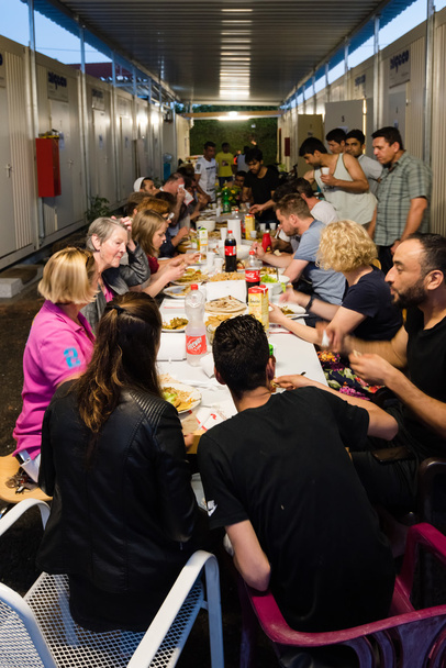 Moslim vluchtelingen en Duitse vrijwilligers zitten samen eten diner tijdens Ramadan vasten maand - Foto, afbeelding