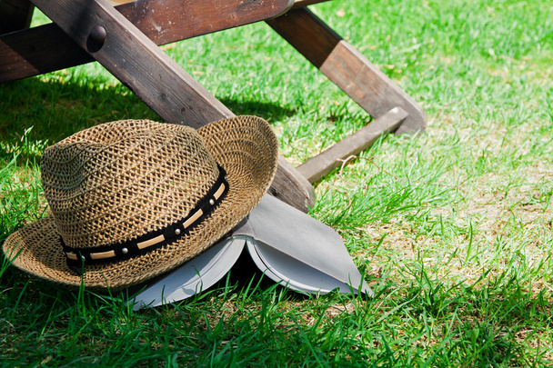 Book and straw hat on grass - 写真・画像