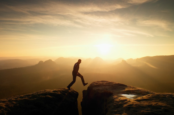 Man in black jumping between peaks. Dreamy daybreak - Photo, Image
