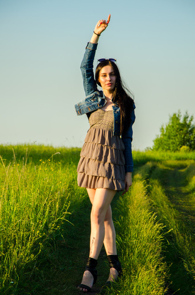 Brunette walks on a green meadow. - Zdjęcie, obraz