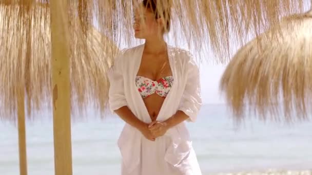 Woman in bikini and beach top under umbrella - Materiał filmowy, wideo