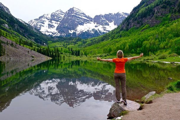 Mujer de pie junto al lago con vistas a las montañas y reflexión
.  - Foto, imagen