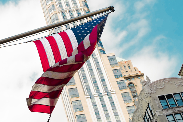 America USA flag waving building street city. - Foto, imagen