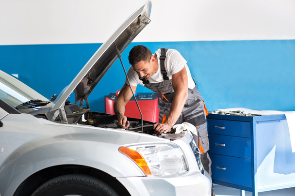 Mechanic repairing a lifted car - Foto, afbeelding